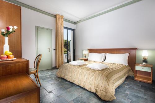 a bedroom with a bed and a table and a chair at Hotel Zeus in Cesenatico