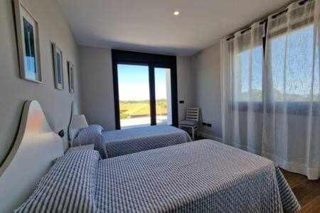 a bedroom with two beds and a large window at Chalet A un paso de Llanes in Llanes