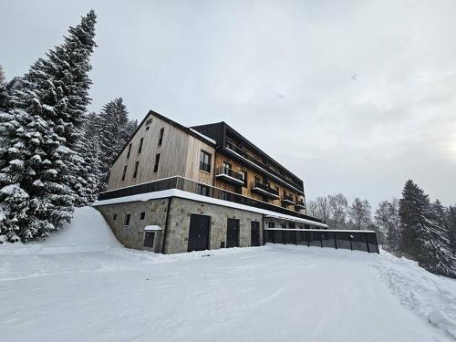 a large building in the snow with snow covered trees at Benecko s možností wellness - A30 by AlkaTravel in Benecko