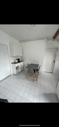 une chambre avec une table et une cuisine avec des placards blancs dans l'établissement Petit Appartement à Uriage, à Vaulnaveys-le-Haut