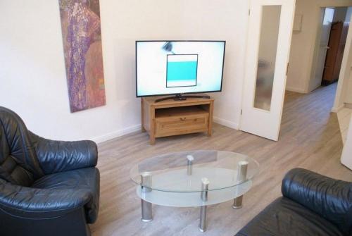 uma sala de estar com uma televisão e uma mesa de café em vidro em Altstadtleben - ABC164 em Wismar