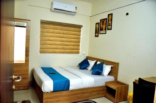 Un dormitorio con una cama con almohadas azules y una ventana en MARHABA PALACE en Kozhikode