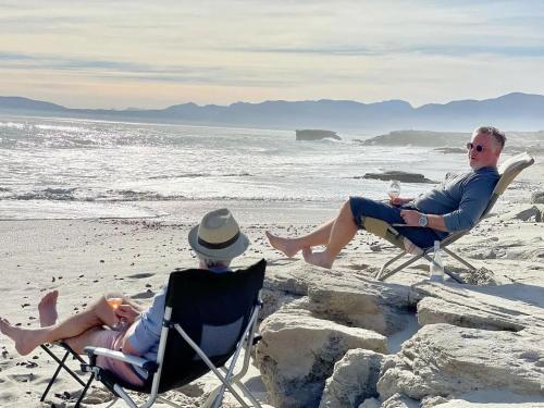 two men sitting in lawn chairs on the beach at The Log House in Pearly Beach