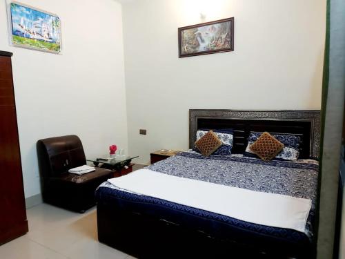 a bedroom with a large bed and a chair at Embassy inn Guest House Hyderabad in Hyderabad
