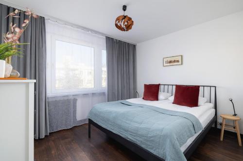 Un dormitorio con una cama con almohadas rojas y una ventana en Comfortable Two-Bedroom Apartment Strzelców by Renters, en Cracovia