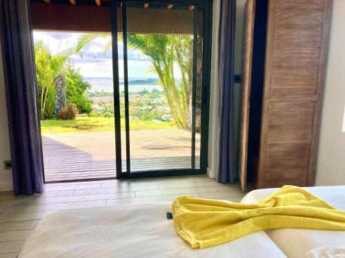 sypialnia z łóżkiem i przesuwnymi szklanymi drzwiami w obiekcie Villa Teranga avec vue panoramique sur la baie de Tamarin w mieście Tamarin