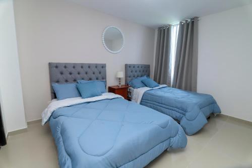 a bedroom with two beds with blue pillows at Comodo y amplio apartamento en Valledupar cerca al Parque la Leyenda in Valledupar