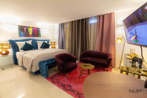 1 Schlafzimmer mit einem Bett und 2 Stühlen sowie einem Flachbild-TV in der Unterkunft BS Luxury Estate El Campello in El Campello