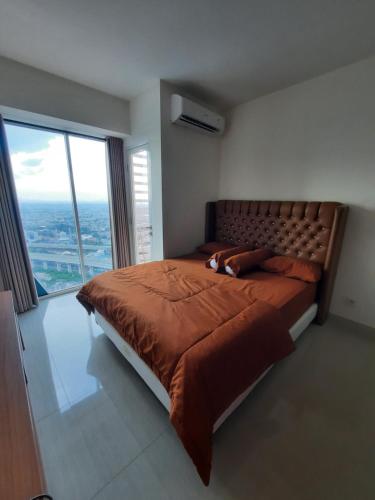 a bedroom with a large bed with a large window at APARTMENT GRAND KAMALA LAGOON MY KIDS in Pulosirih