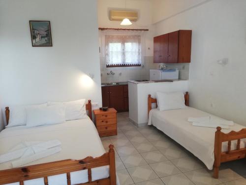 een slaapkamer met 2 bedden en een kleine keuken bij Pansion Katerina Skyros in Acherounes