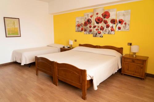 2 Betten in einem Zimmer mit gelben Wänden in der Unterkunft Albergo San Lorenzo in Grosseto