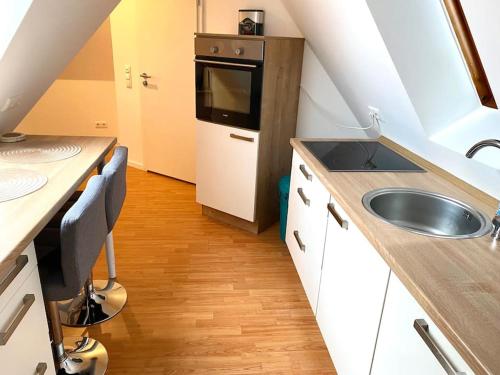 una pequeña cocina con fregadero y microondas en gemütliches Apartment Döhren, en Hannover