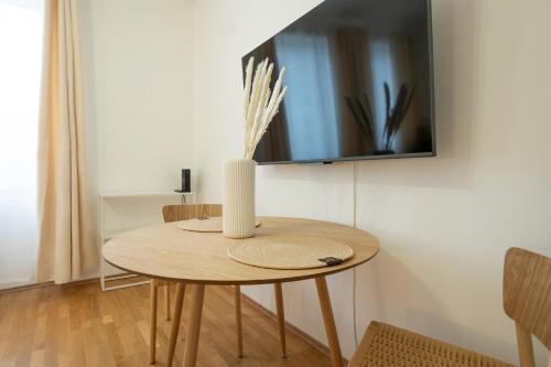 einen Holztisch mit einer Vase darüber in der Unterkunft Bright and cozy studio with a city view in Wien