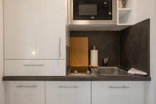 eine Küche mit einer Spüle und einer Mikrowelle in der Unterkunft Bright and cozy studio with a city view in Wien