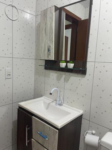 a bathroom with a sink and a mirror at Casa 01,02 in Bombinhas