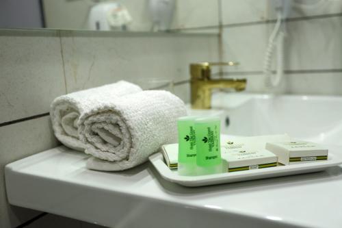 a bathroom counter with towels and a sink at Adhyas Castle in Morbi