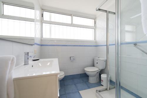een badkamer met een toilet, een wastafel en een raam bij Apartamentos El Capricho in Maspalomas