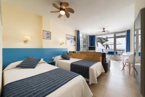 two beds in a room with a view of the ocean at Apartamentos El Capricho in Maspalomas