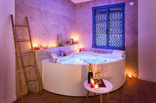 baño con bañera con escalera y ventana en Le Patio d'Arlou & Spa - Relaxant et romantique, en Fabrezan