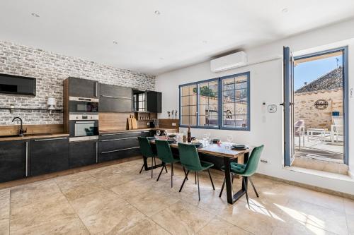 a kitchen and dining room with a table and green chairs at Le Patio d'Arlou & Spa - Relaxant et romantique in Fabrezan
