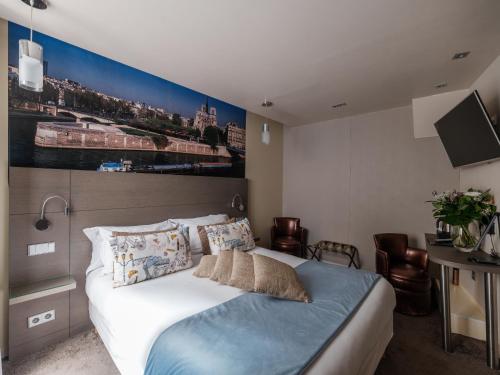 a bedroom with a bed with a large painting on the wall at Hotel Minerve in Paris