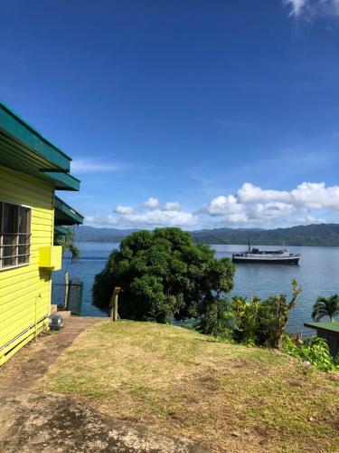 a yellow house with a boat in the water at Limericks by the Sea in Savusavu