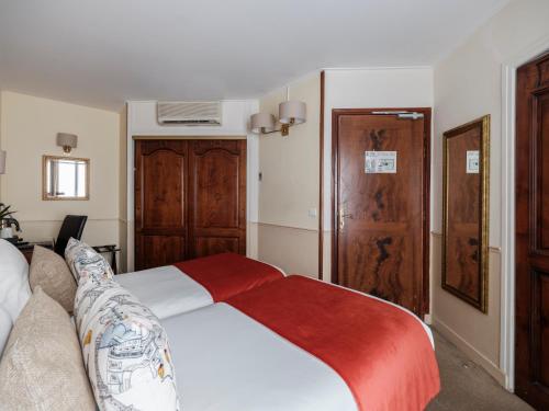 a bedroom with a white bed with a red blanket at Hotel Minerve in Paris