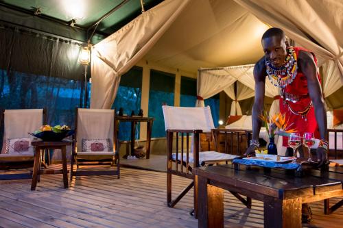 Soroi Mara Bush Camp في ماساي مارا: رجل يقف على طاولة في خيمة