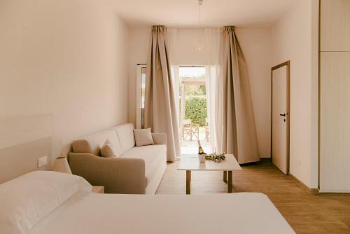 a white bedroom with a couch and a table at Residence Altair - Serra Degli Alimini 3 in Otranto