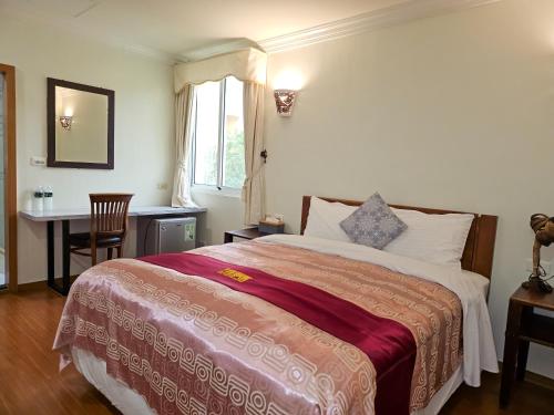 a bedroom with a bed and a desk and a window at Kenting Garden Homestay in Kenting