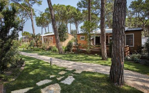 a cabin in the woods with a gravel driveway and trees at Dei Fiori Camping Village in Cavallino-Treporti