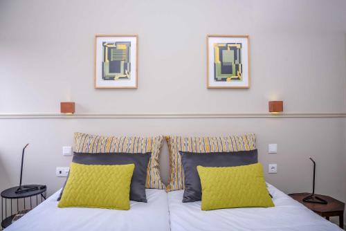 a bed with two pillows and two pictures on the wall at Hotel Singular Porto Aeroporto in Maia