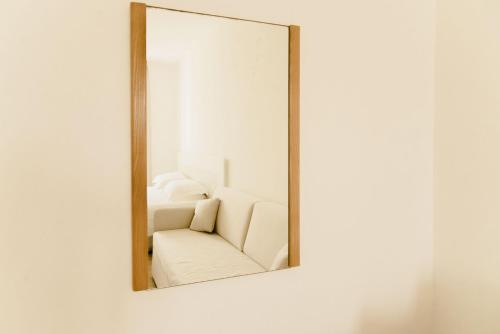 a mirror hanging on a wall with a white couch at Residence Altair - Serra degli Alimini in Otranto