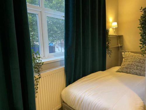 a bedroom with a bed with green curtains and a window at Single Bright Studio Flat in King's Cross in London