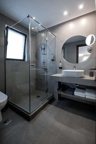 a bathroom with a shower and a sink and a mirror at Pnoe Urban Living in Athens