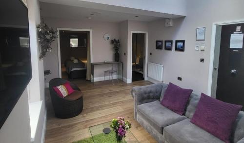 sala de estar con sofá y almohadas moradas en Harrogate Lifestyle Luxury Serviced ApartHotel en Harrogate