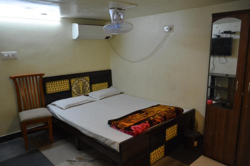 een kleine slaapkamer met een bed en een stoel bij Hotel Garden Residency By WB Inn in Bangalore