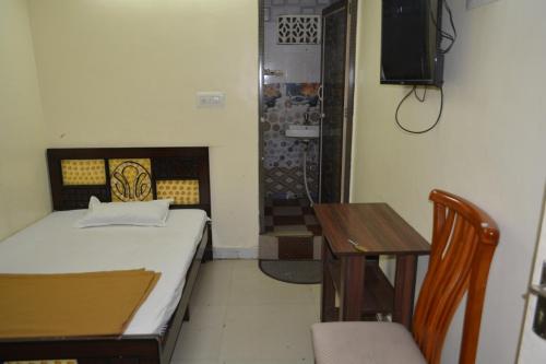 a small room with a bed and a table and a television at Hotel Garden Residency By WB Inn in Bangalore