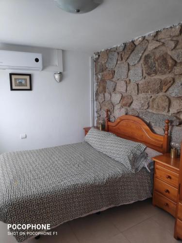 um quarto com uma cama e uma parede de pedra em Apartamento independiente en plena naturaleza Vallromanes Barcelona em Vallromanes