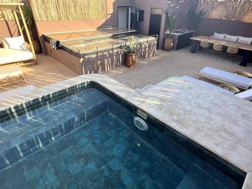 a swimming pool in a patio with chairs and tables at RIAD LE M neuf et contemporain in Marrakesh