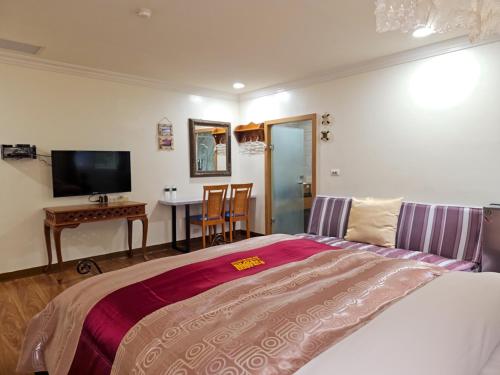 a bedroom with a bed and a table and a television at Kenting Garden Homestay in Kenting