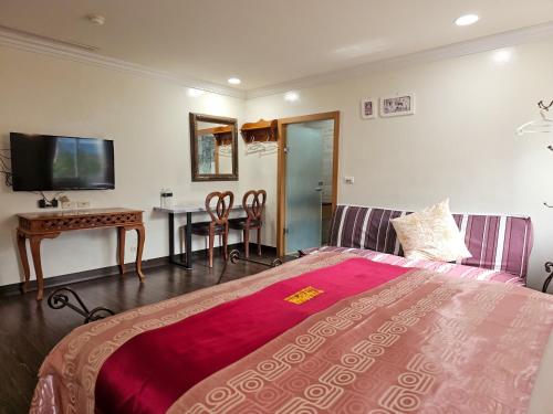 a bedroom with a bed and a table and a television at Kenting Garden Homestay in Kenting