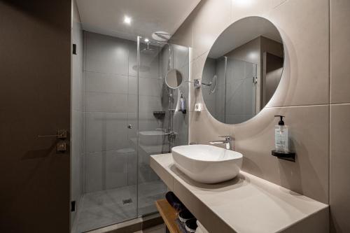 a bathroom with a sink and a shower with a mirror at Pnoe Urban Living in Athens
