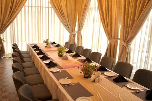 a long table with chairs in a room with windows at Ramada by Wyndham Aligarh GT Road in Alīgarh