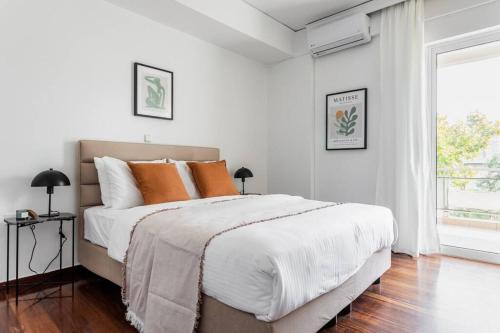 a white bedroom with a large bed with orange pillows at Capacious 3BR apartment in the heart of Marousi in Athens