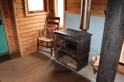 a wood stove in a room with a chair at Shepherd's Loch Glamping in Turriff