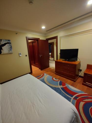 a bedroom with a bed and a flat screen tv at فندق كارم العليا in Al Khobar