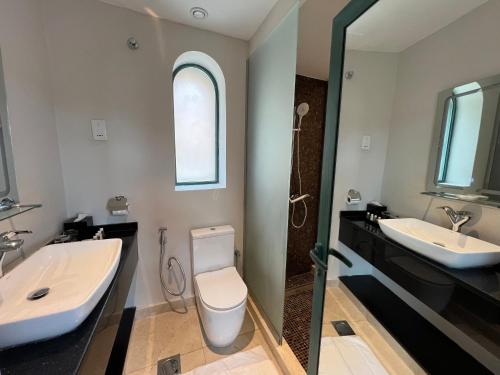 a bathroom with two sinks and a toilet and a mirror at Dibba Mountain Park Resort in Fujairah
