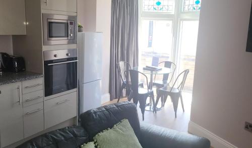 Harrogate Lifestyle Luxury Serviced ApartHotel في هاروغايت: غرفة معيشة مع أريكة ومطبخ مع طاولة