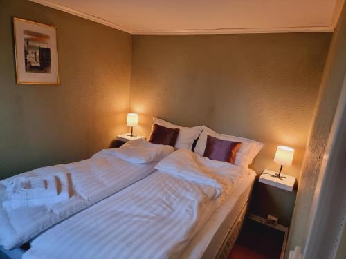 een groot bed met witte lakens en kussens in een slaapkamer bij Kjellerleilighet egen inngang. in Stange
